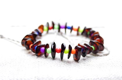 Daudzkrāsainā aproce. Ķiršu krāsas pulēts čipsu formas Baltijas dzintars ar spilgtām daudzkrāsainām akrila pērlītēm